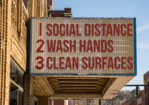 Movie marquee with COVID-19 notices to social distance, wash hands, and clean surfaces
